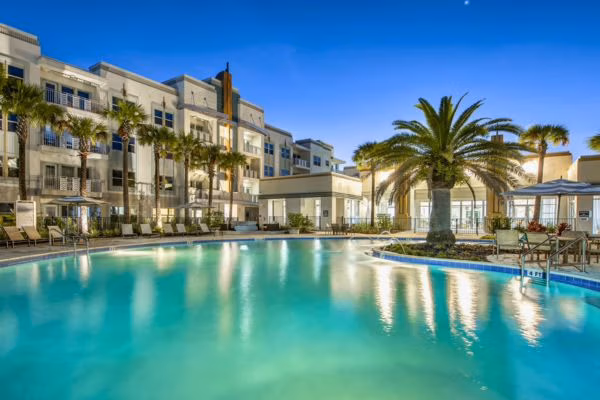 Large resort-style pool surrounded by palm trees at Astoria student housing