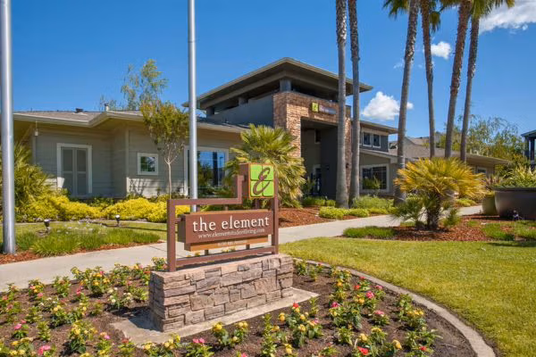 Entry sign and clubhouse at The Element student housing with landscaped grounds